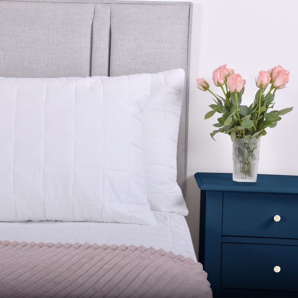 A pair of 100% cotton quilted pillow protectors on a bed 