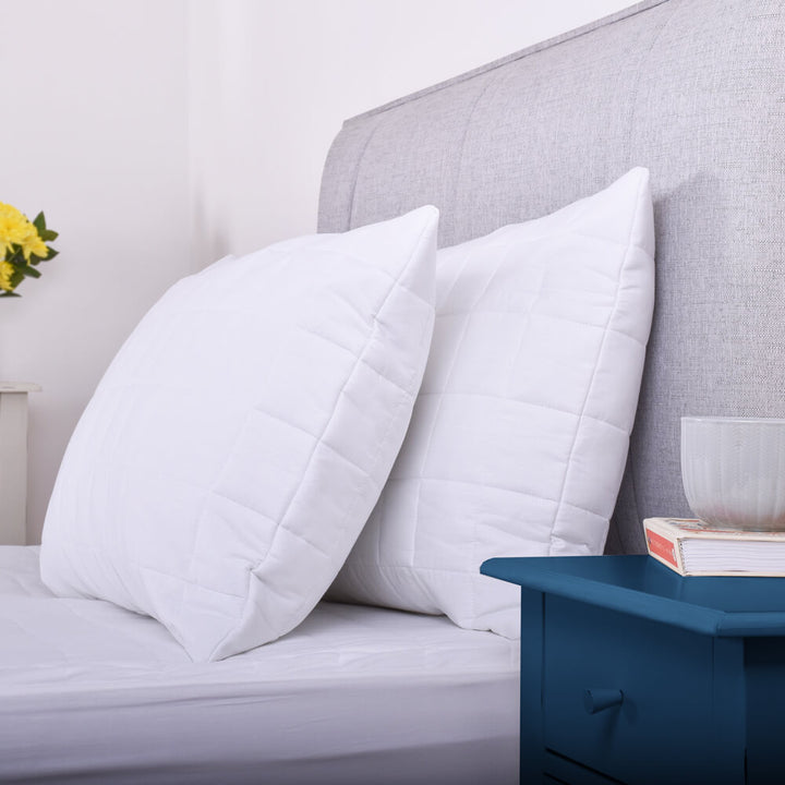 Side view of a pair of 100% cotton quilted pillow protectors on a bed 