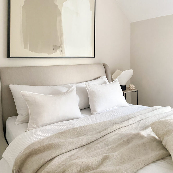 Duck feather filled bolster pillow with 100% cotton cover and a polycotton pillowcase on a bed with standard pillows
