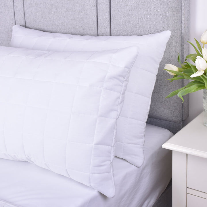 Top view of a pair of 100% cotton quilted pillow protectors on a bed 