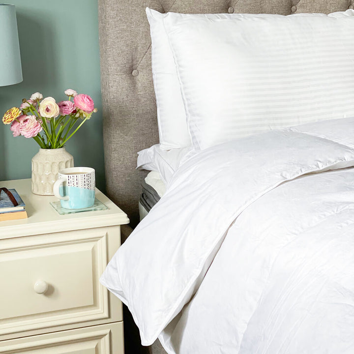 Goose feather and goose down duvet, encased in 100% cotton. The duvet is draped over a bed.