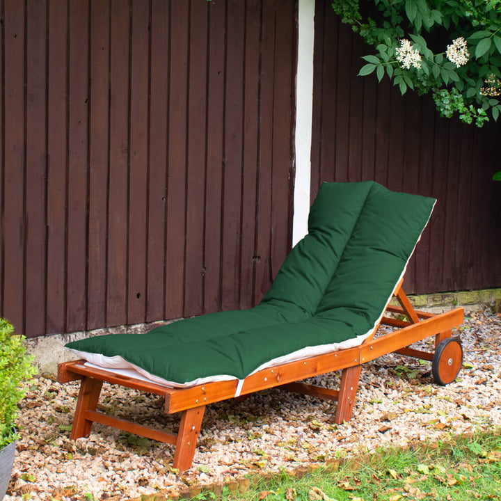 Lancashire Textiles Bottle Green Sun Lounger Topper on a wooden sun lounger in a garden. 