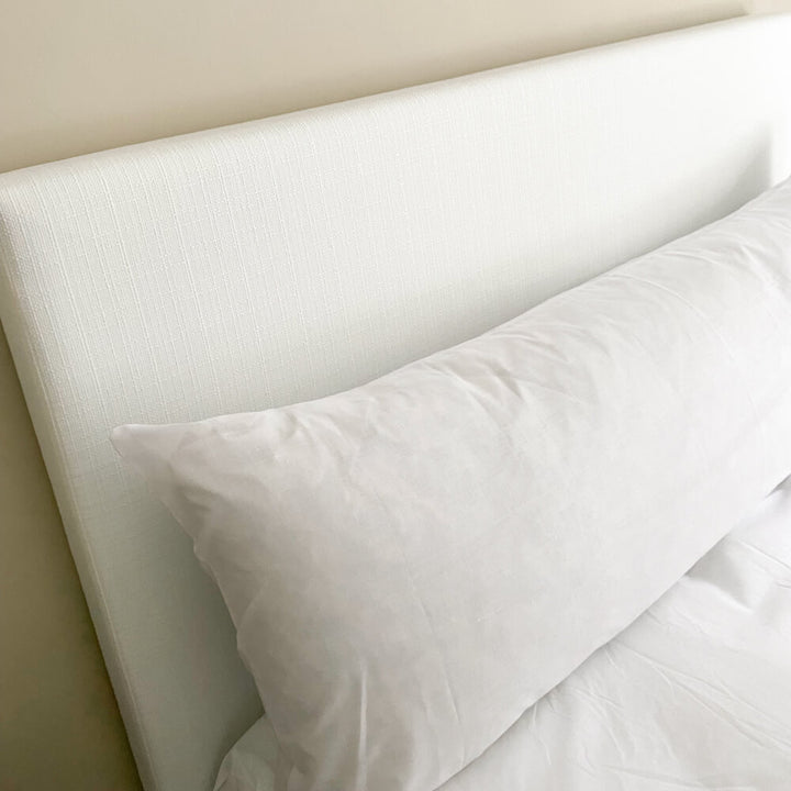 Duck feather filled bolster pillow with 100% cotton cover with a pillowcase on a bed