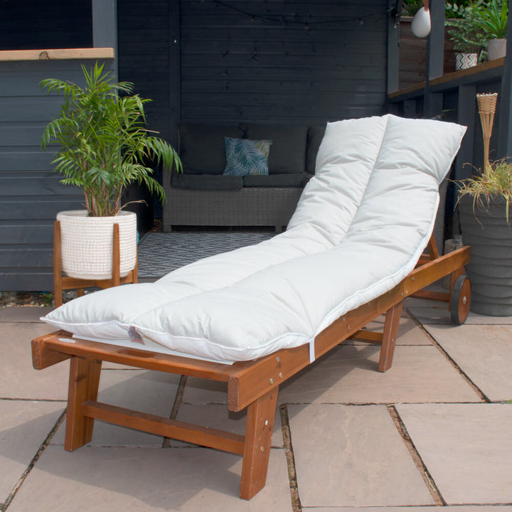 Lancashire Textiles light grey Sun Lounger Topper on a wooden sun lounger in a garden. 