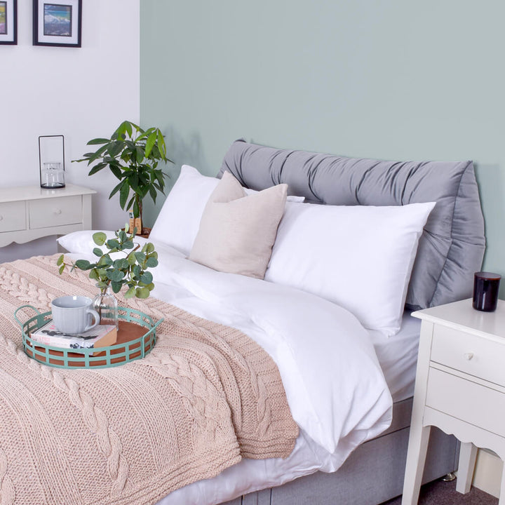 Grey velvet headboard wedge pillow on bed with pillows and duvet