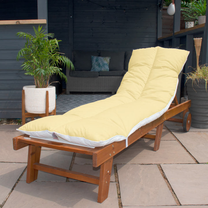 Lancashire Textiles Lemon Yellow Sun Lounger Topper on a wooden sun lounger in a garden. 