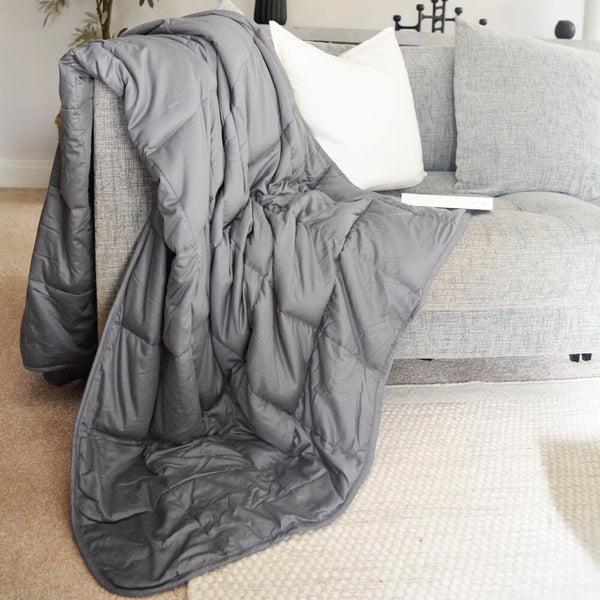 100% grey cotton weighted blanket draped over sofa arm