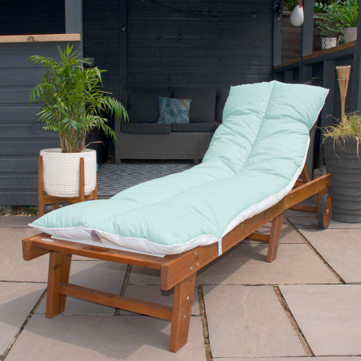 Lancashire Textiles mint Sun Lounger Topper on a wooden sun lounger in a garden. 