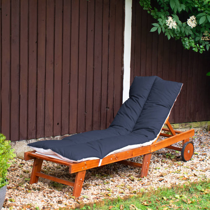 Lancashire Textiles Navy Blue Sun Lounger Topper on a wooden sun lounger in a garden. 