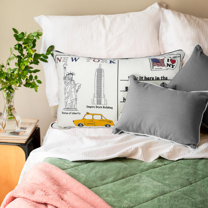 New York Postcard Themed cushion on a bed with other scatter cushions