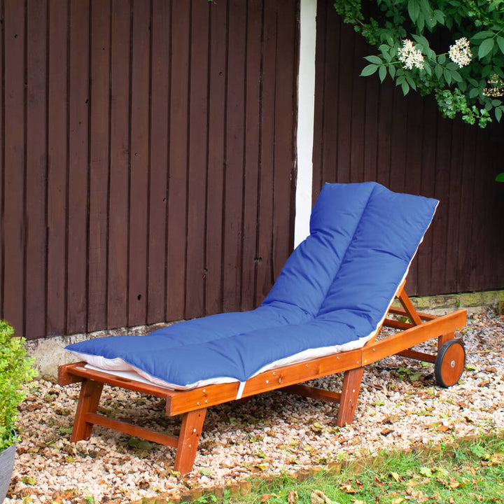 Lancashire Textiles Royal Blue Sun Lounger Topper on a wooden sun lounger in a garden. 