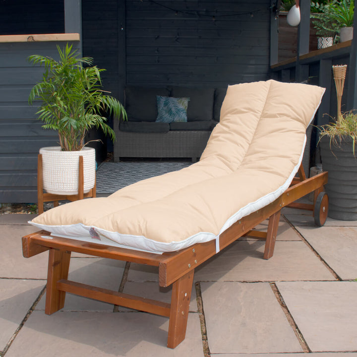 Lancashire Textiles sand Sun Lounger Topper on a wooden sun lounger in a garden. 