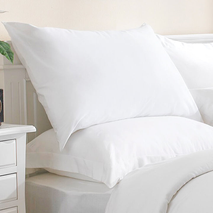 100% cotton, white pillowcases on pillows on a bed
