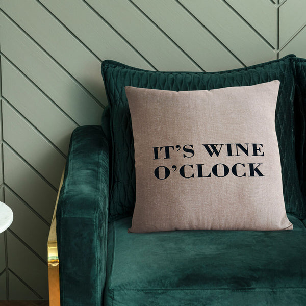 Natural coloured cushion cover with typography "It's Wine O' Clock'. 43cm x 43cm. Cover shown on cushion (not included) on a green velvet sofa